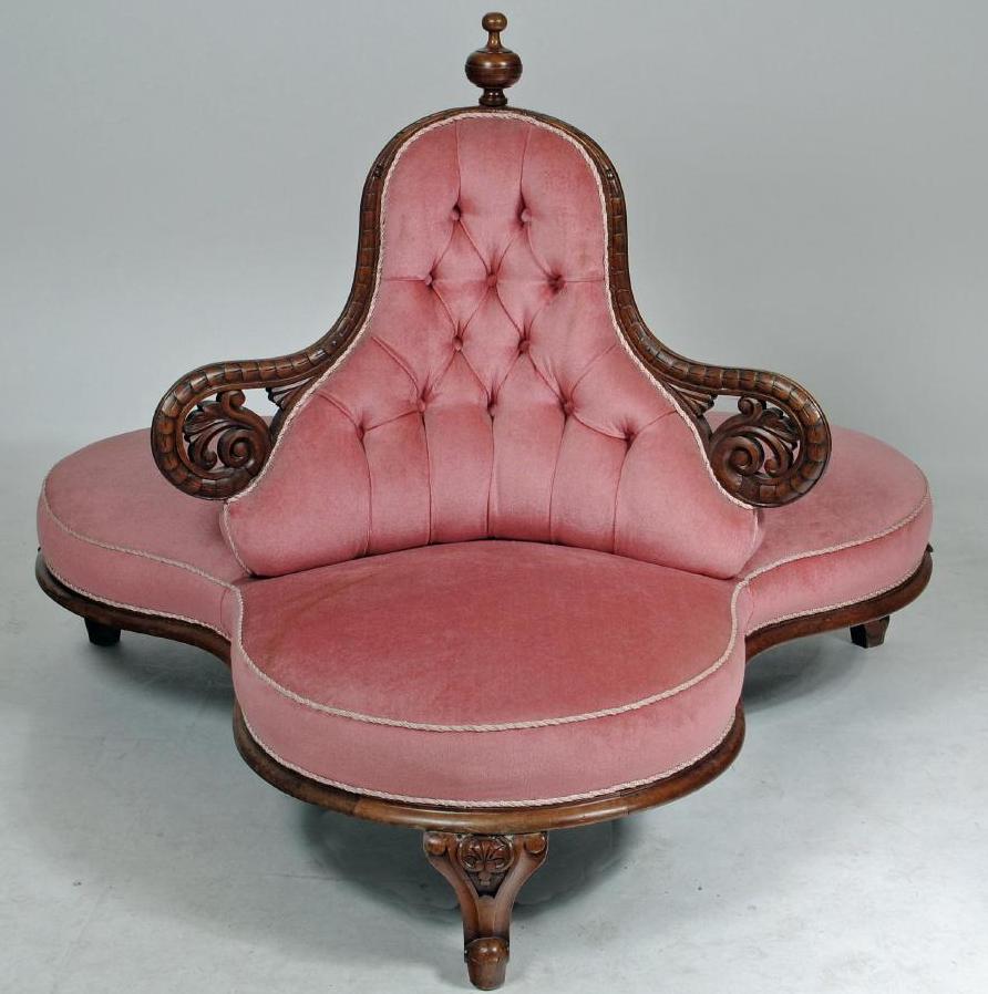 A VICTORIAN WALNUT FRAMED CHAPERONE SOFA button upholstered in pink dralon and surmounted by a Image