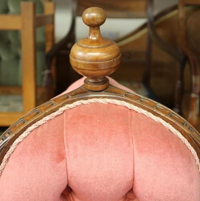 A VICTORIAN WALNUT FRAMED CHAPERONE SOFA button upholstered in pink dralon and surmounted by a Image