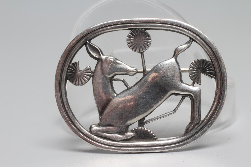 A GEORG JENSEN SILVER OVAL BROOCH designed by Arno Malinowski with a kneeling deer amongst flowers, Image