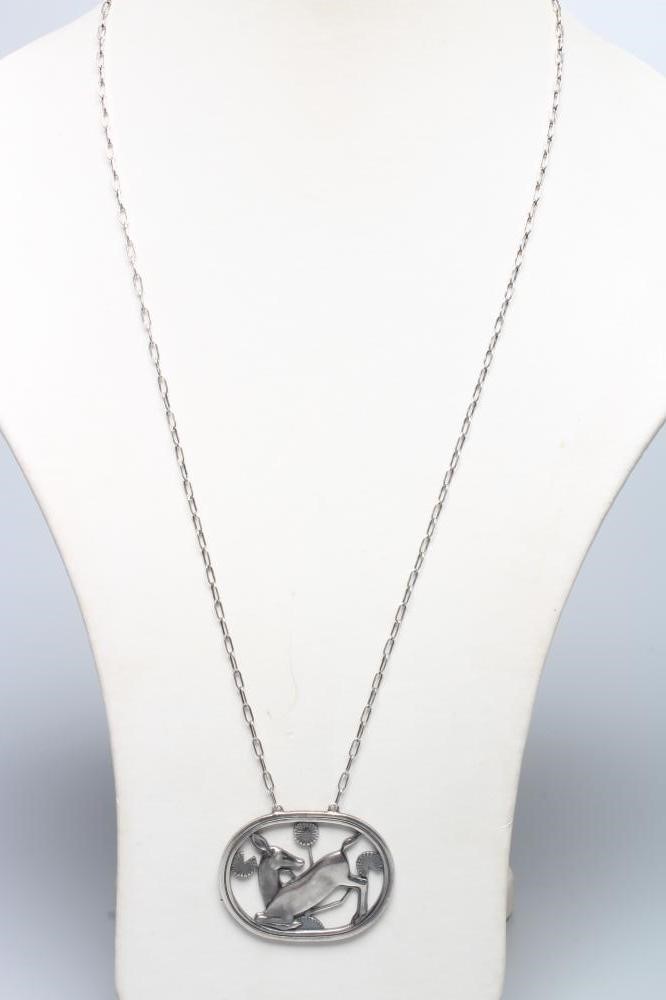 A GEORG JENSEN SILVER OVAL PENDANT designed by Arno Malinowski with a kneeling deer amongst flowers, Image