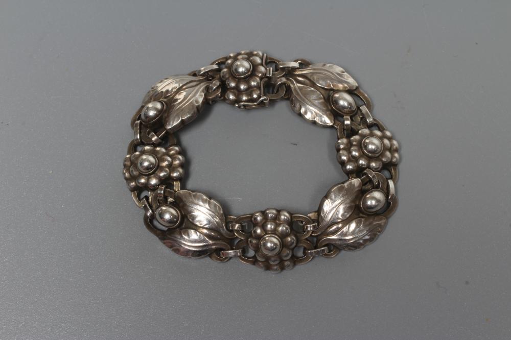 A GEORG JENSEN SILVER BRACELET designed by Georg Jensen with stylised flowerheads and two leaves Image