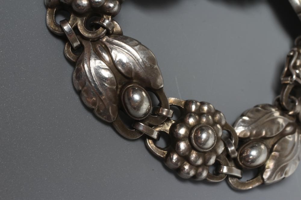 A GEORG JENSEN SILVER BRACELET designed by Georg Jensen with stylised flowerheads and two leaves Image