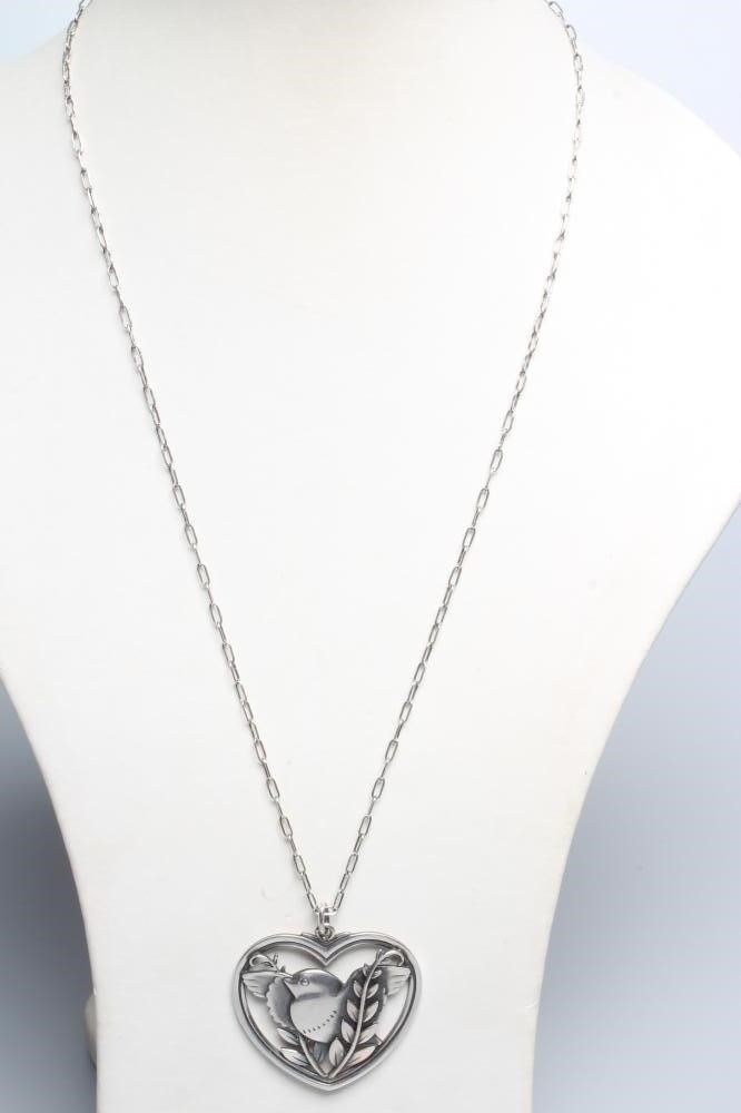 A GEORG JENSEN SILVER DOVE IN HEART PENDANT designed by Arno Malinowski, stamped Sterling 97, on an Image