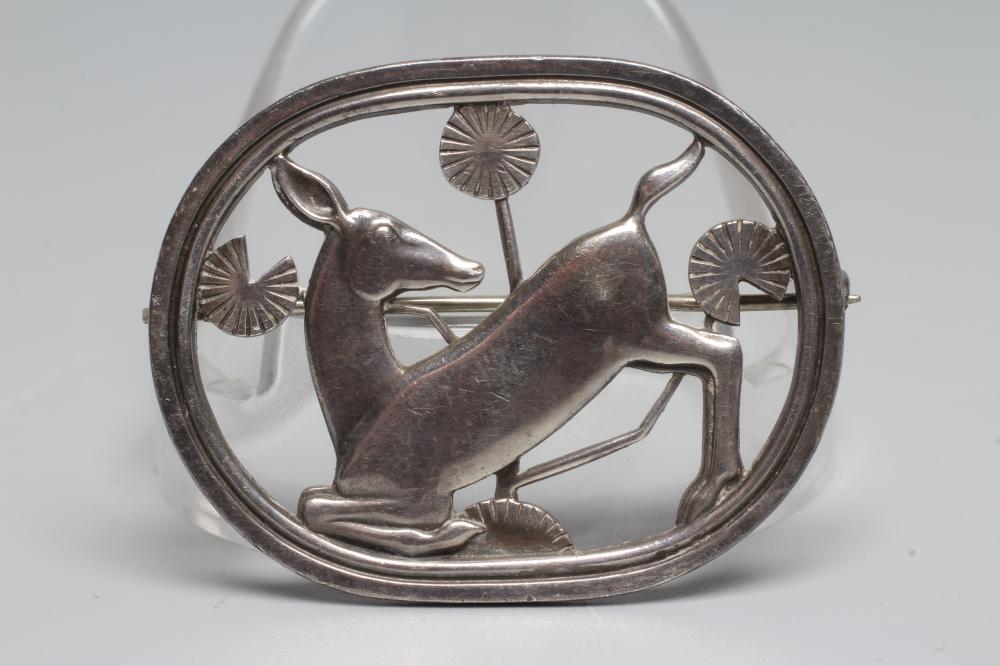 A GEORG JENSEN SILVER OVAL BROOCH designed by Arno Malinowski with a kneeling deer amongst flowers, Image