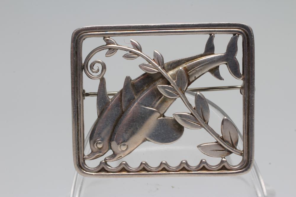 A GEORG JENSEN SILVER OBLONG BROOCH designed by Arno Malinowski as two dolphins swimming amidst Image