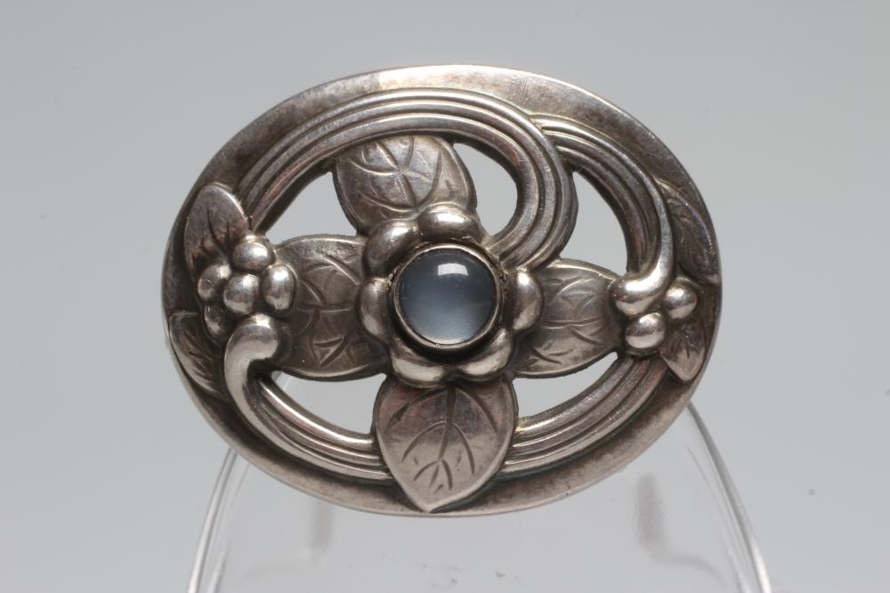 A GEORG JENSEN SILVER OVAL BROOCH designed by Georg Jensen as a stylised flowerhead centred by a Image
