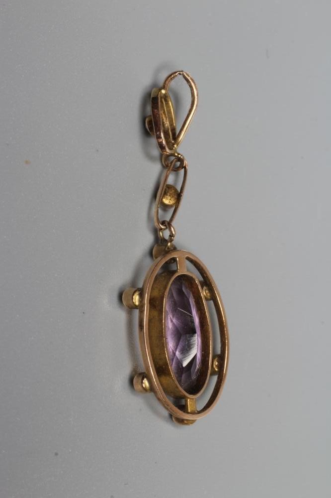 AN EDWARDIAN AMETHYST AND SEED PEARL PENDANT, the oval facet cut amethyst collet set to an open Image