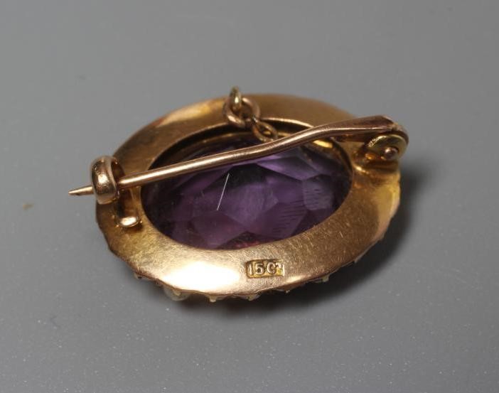 A LATE VICTORIAN OVAL AMETHYST BROOCH centred by a facet cut stone within a border of seed pearls to Image