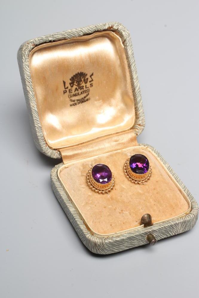A PAIR OF AMETHYST EAR STUDS, the oval facet cut stones in deep collets with twisted borders to Image