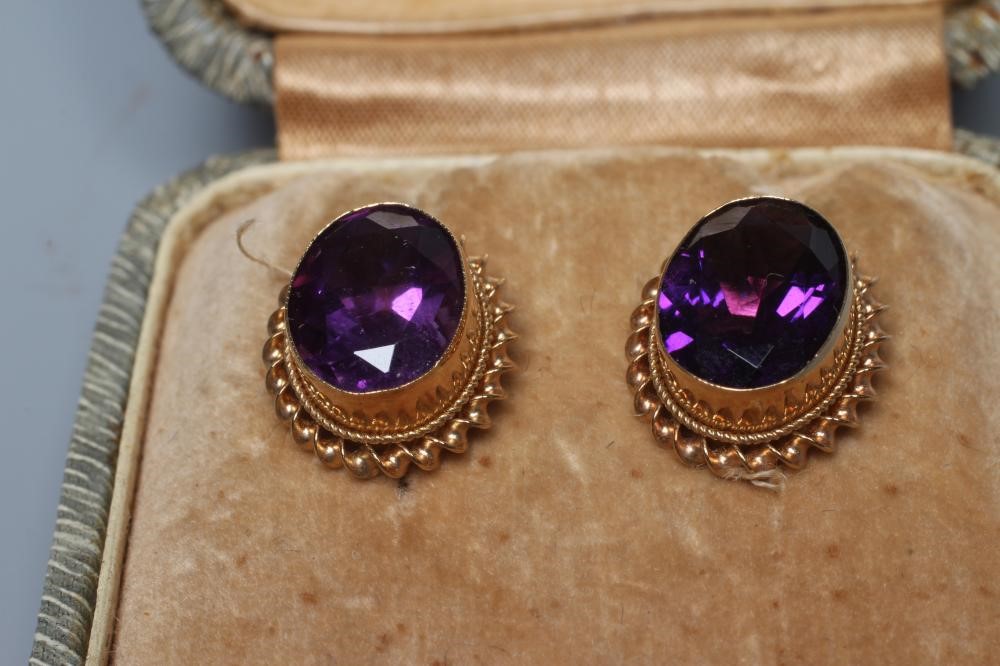 A PAIR OF AMETHYST EAR STUDS, the oval facet cut stones in deep collets with twisted borders to Image