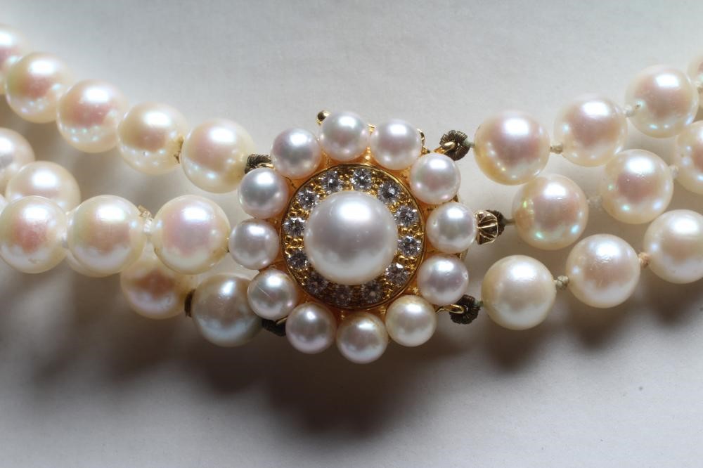 A TRIPLE STRAND CULTURED PEARL NECKLACE, the uniform pearls strung to a diamond and pearl 18ct gold Image