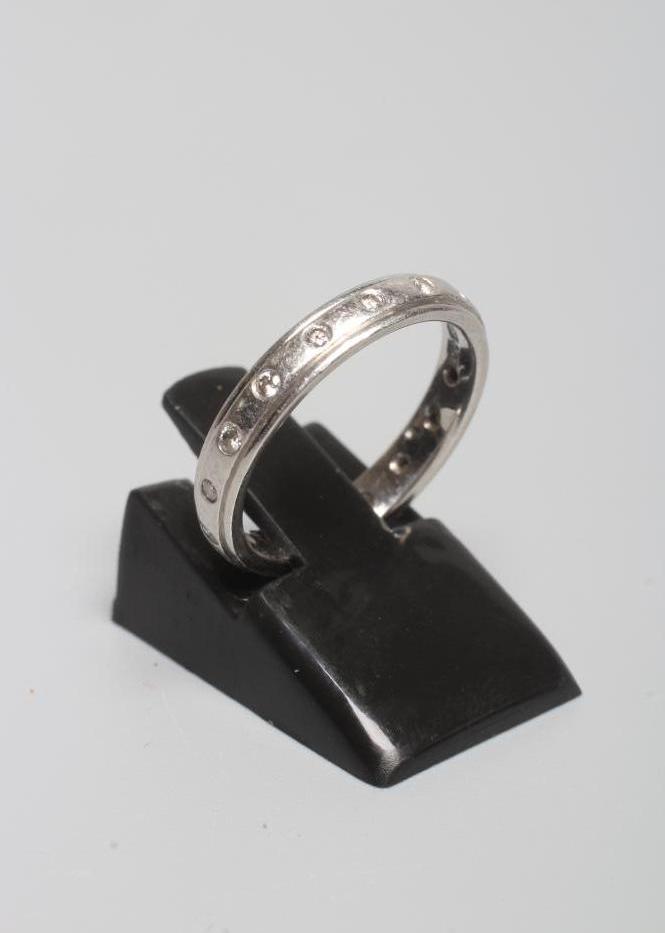 A PLATINUM ETERNITY RING with small diamonds in rub-over settings, London, 5.1g gross, size J 1/2 Image
