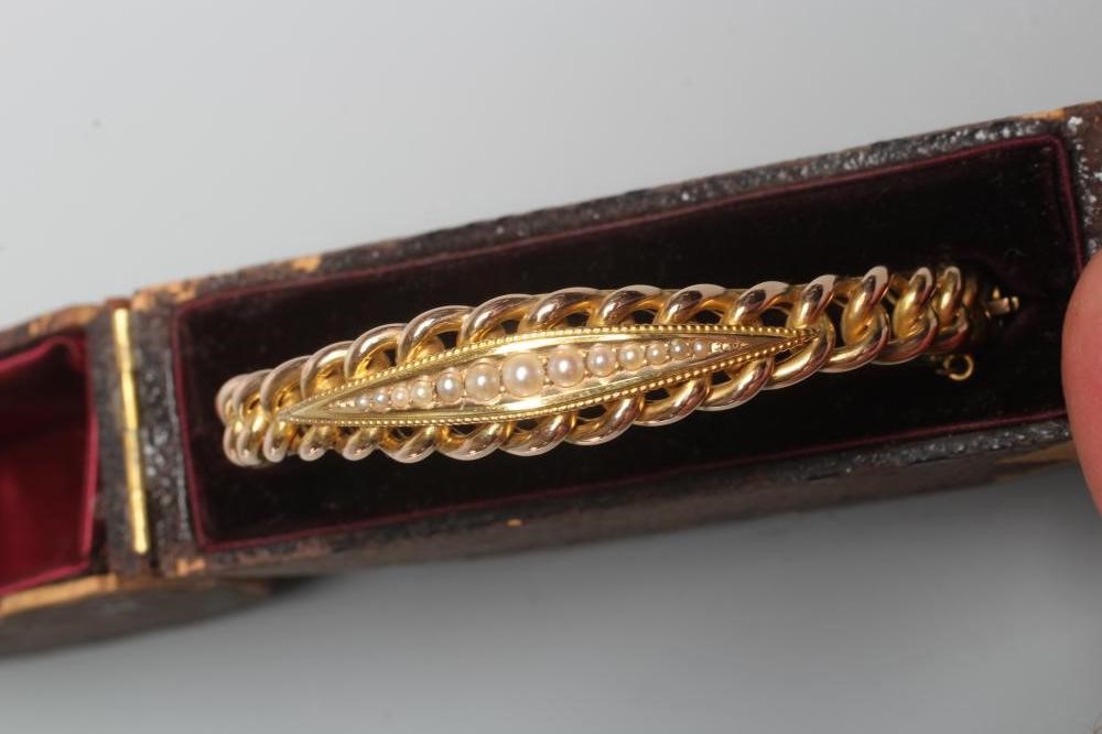 A LATE VICTORIAN ROPE TWIST STIFF HINGED BANGLE, unmarked, the upper section centred by an eliptical Image