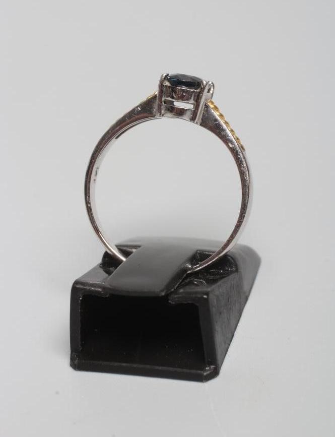 A SOLITAIRE SAPPHIRE RING, the oval facet cut stone claw set to yellow rope twist set shoulders and Image