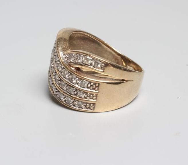 A DIAMOND COCKTAIL RING point set with three diagonal lines of ten small stones with a single Image