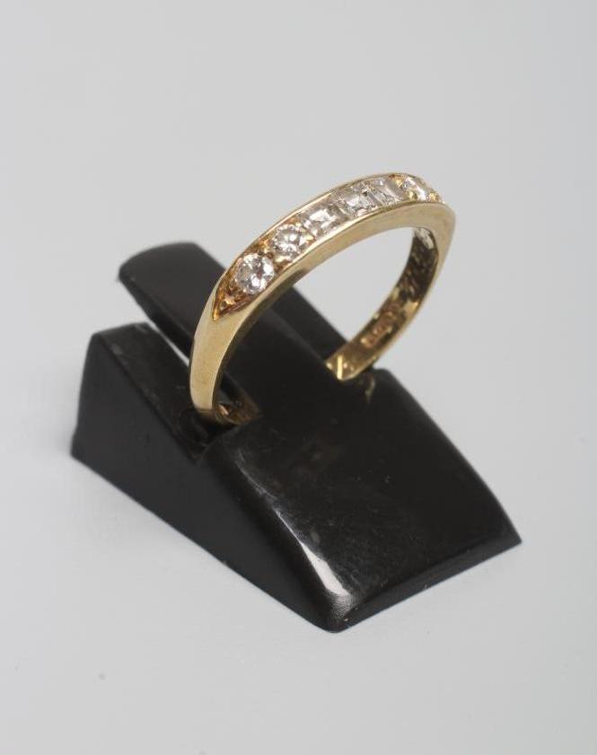 A SEVEN STONE DIAMOND HALF HOOP ETERNITY RING centrally channel set with three emerald cut stones Image
