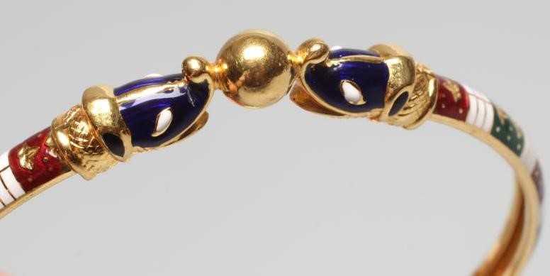 A BANGLE, unmarked but probably Egyptian, with red, white and green enamelled arcading and snake Image