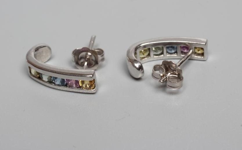 A PAIR OF MULTI-GEM EAR STUDS channel set with five coloured stones to 9ct white gold curved panels, Image