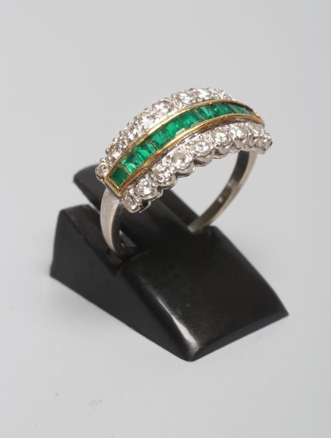 AN EMERALD AND DIAMOND HALF HOOP RING channel set with eleven square cut emeralds within borders Image
