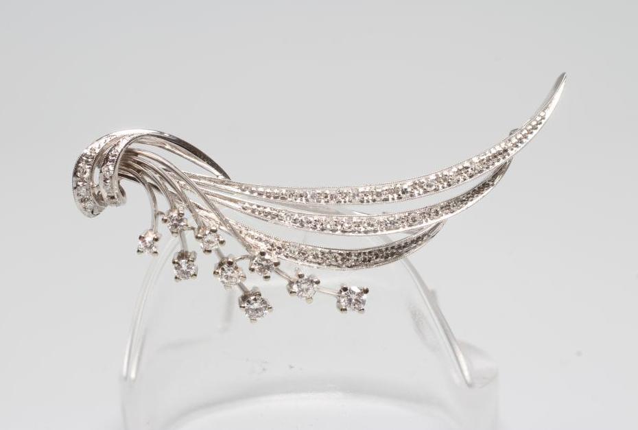 A DIAMOND SPRAY BROOCH, the three stylised curved leaves point set with graduated small stones and Image