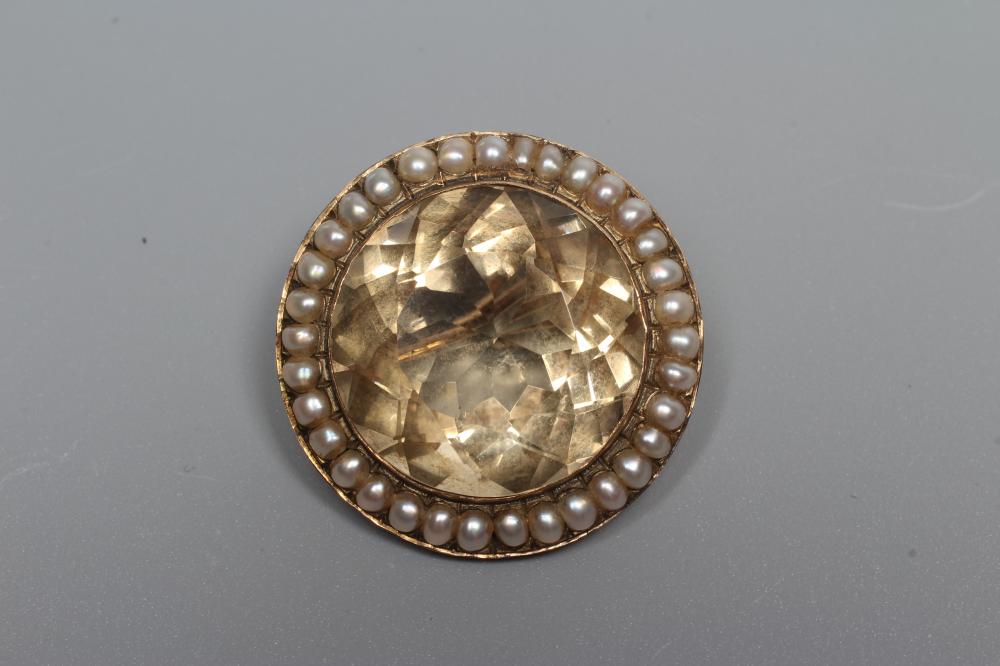 A VICTORIAN CITRINE BROOCH, the circular facet cut stone collet set to a border of small pearls Image