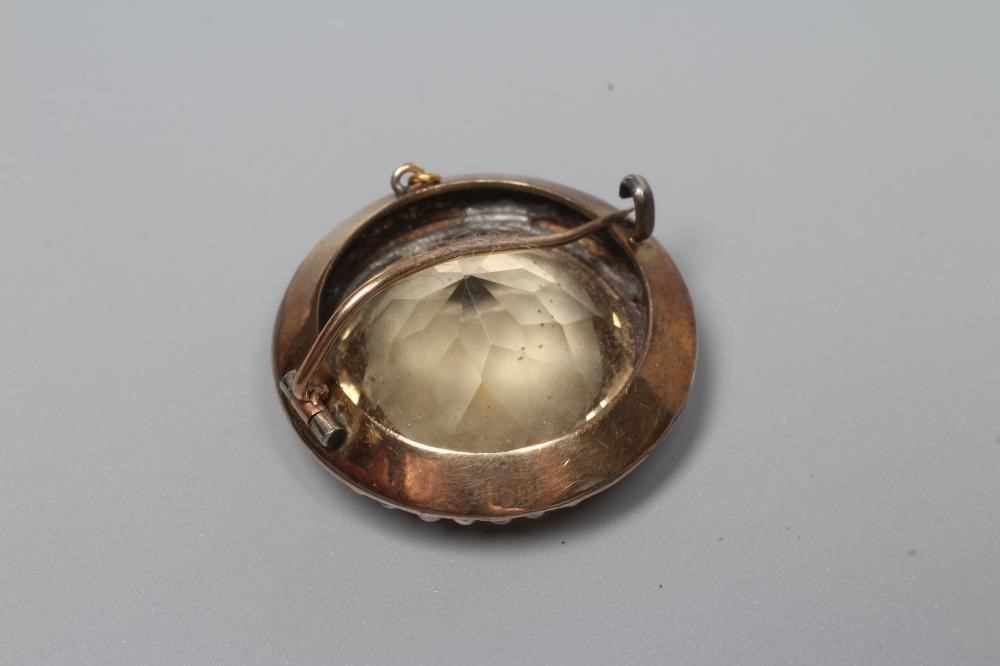 A VICTORIAN CITRINE BROOCH, the circular facet cut stone collet set to a border of small pearls Image