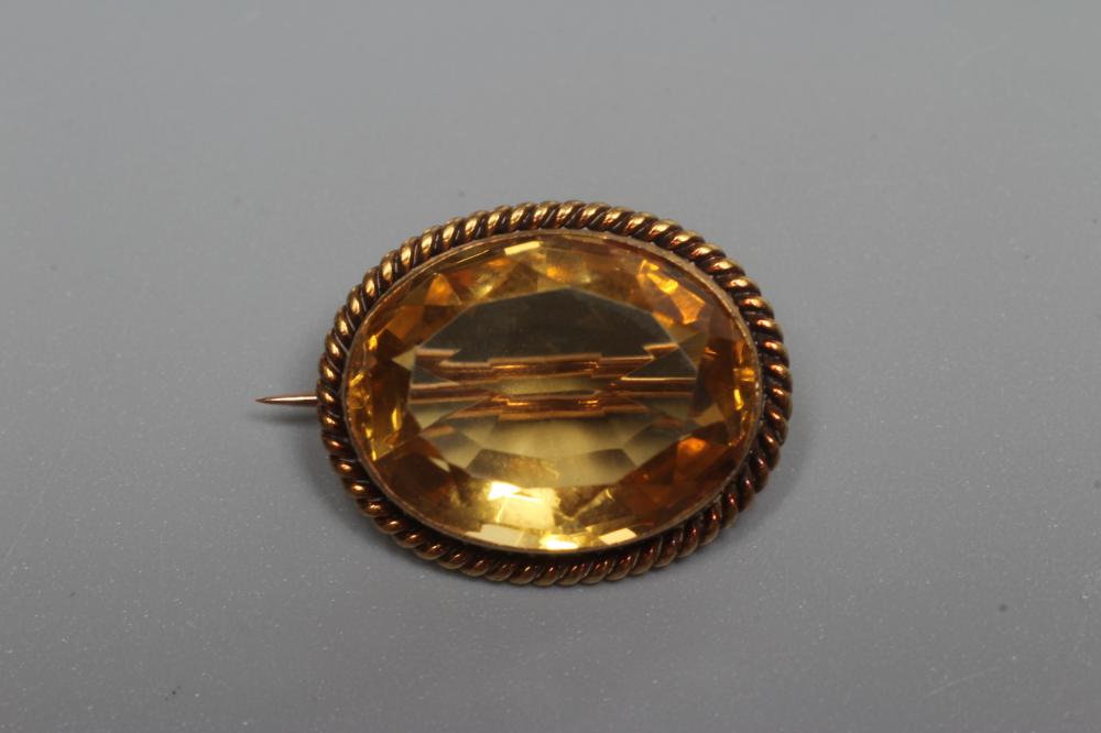 AN OVAL CITRINE SMALL BROOCH, the facet cut stone collet set to an unmarked rope twist frame (Est. Image