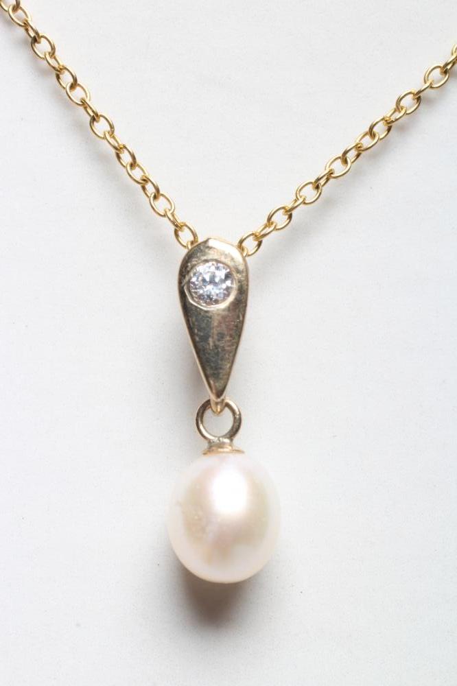 A CULTURED PEARL PENDANT, the white oval pearl peg set to a triangular 9ct gold bale set with a Image
