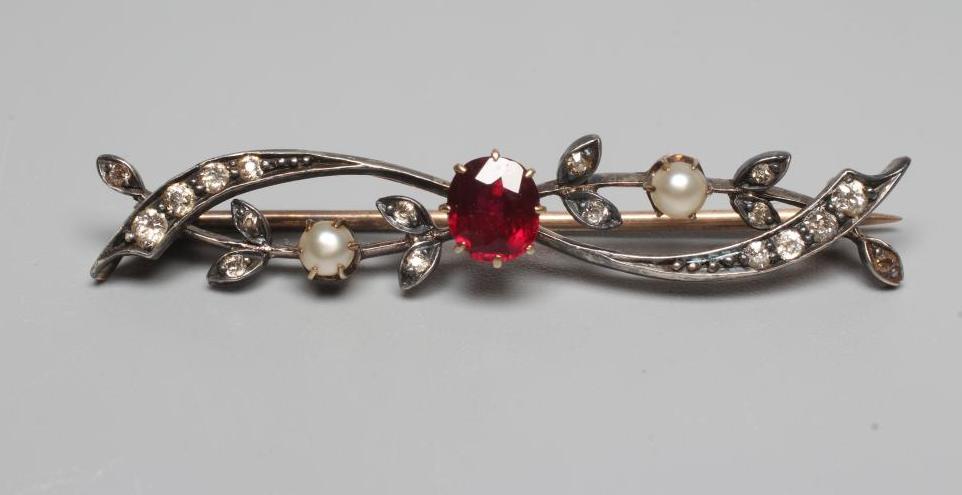 A LATE VICTORIAN BROOCH centred by a facet cut ruby claw set to scrolls set with small diamonds and Image