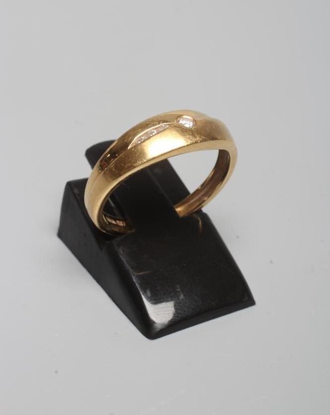 A DIAMOND RING with a single small stone in rub-over setting beside three smaller channel set stones Image