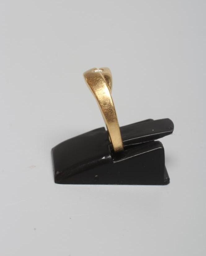 A DIAMOND RING with a single small stone in rub-over setting beside three smaller channel set stones Image