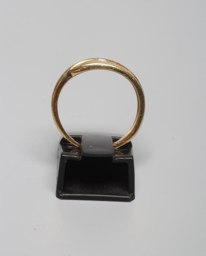 A DIAMOND RING with a single small stone in rub-over setting beside three smaller channel set stones Image