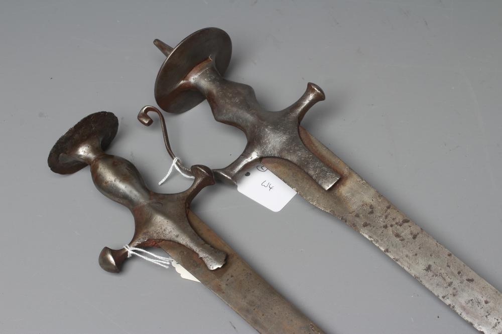 TWO INDIAN TALWAR both with curved blades, extended langets, twin quillon and disc pommels, one with Image