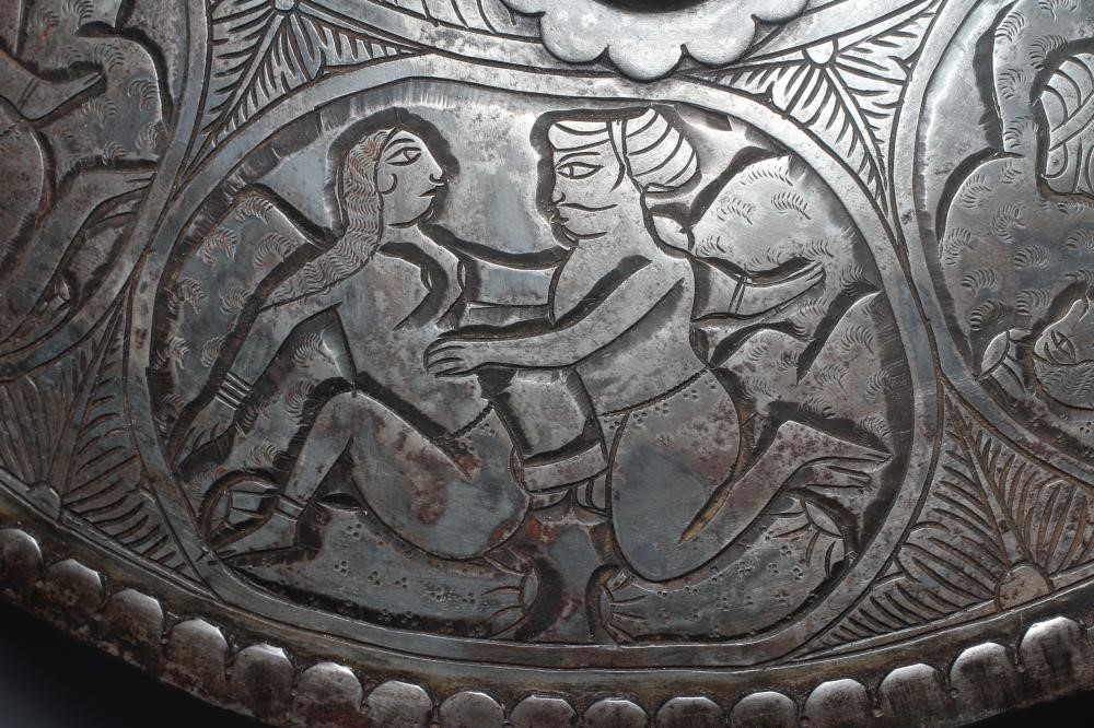 AN INDIAN STEEL CIRCULAR DHAL SHIELD with four bosses and decorated with erotic scenes, 17" diameter Image