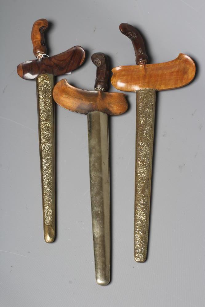 THREE INDONESIAN KRIS DAGGERS with shaped and laminated steel blades, carved grips and typical two Image