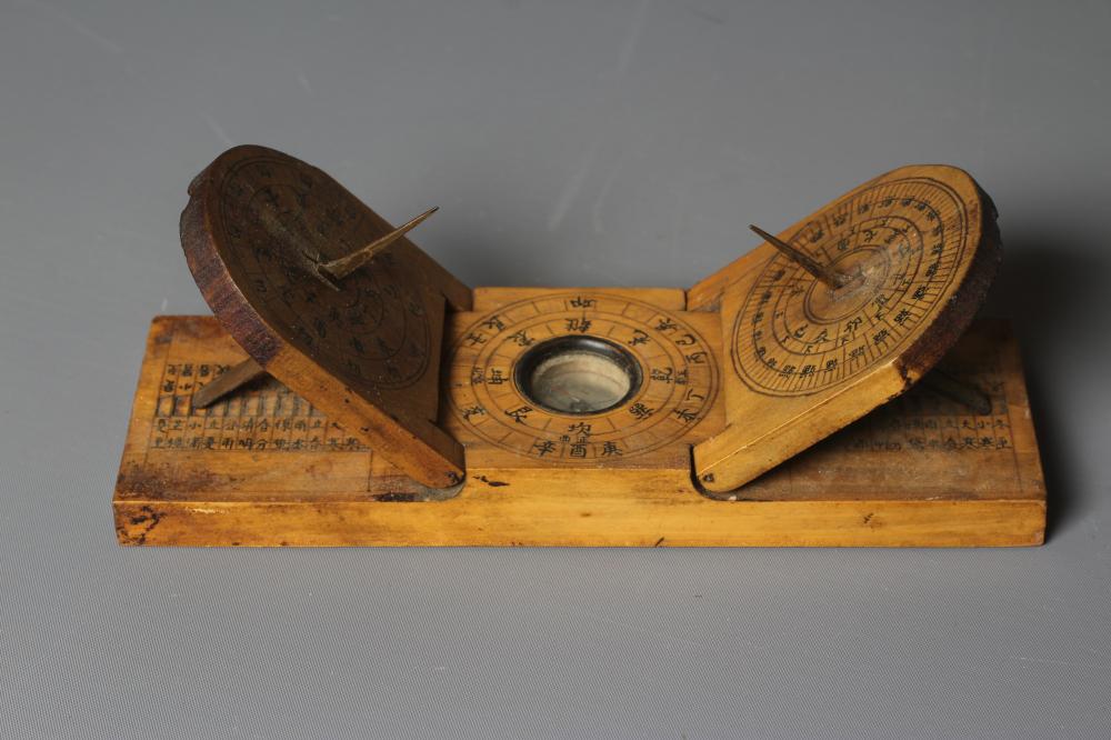 A CHINESE WOOD COMPASS FLANKED BY TWO SUNDIALS Image