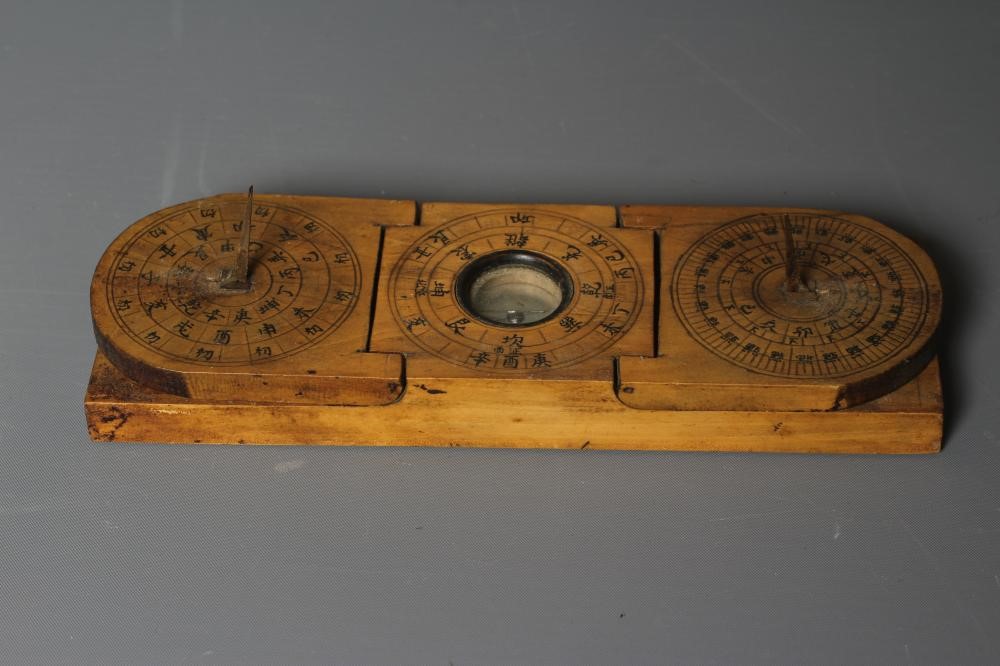 A CHINESE WOOD COMPASS FLANKED BY TWO SUNDIALS Image