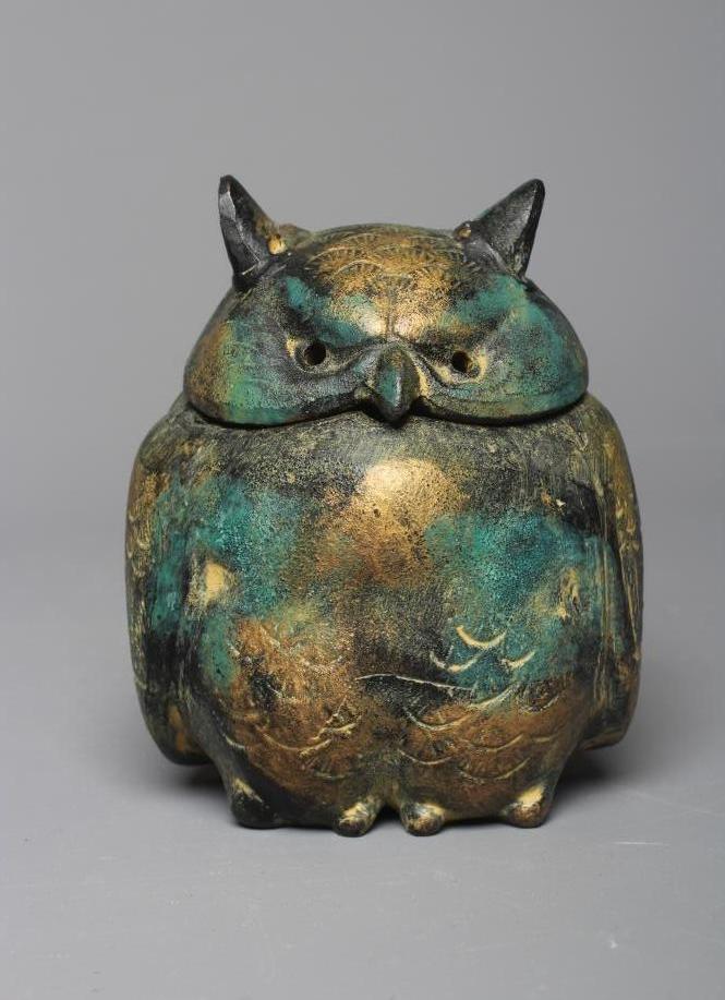 A JAPANESE GREEN PATINATED METAL OWL BOX, modern, the head forming the cover, with gilded Image