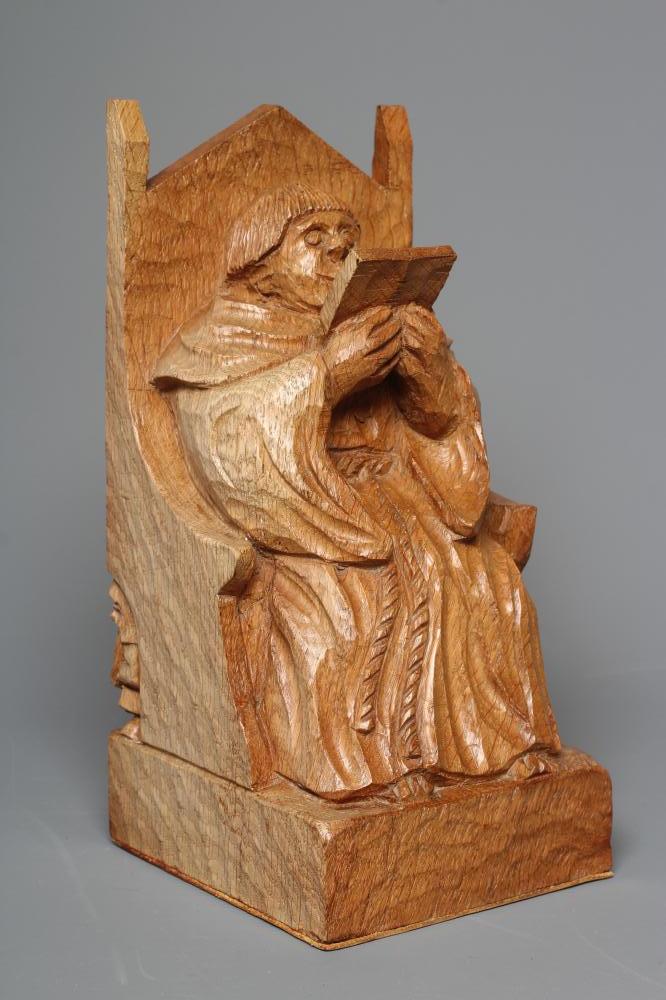 A THOMAS WHITTAKER FIGURAL BOOKEND carved as a friar reading a book and seated in an ecclesiastical Image
