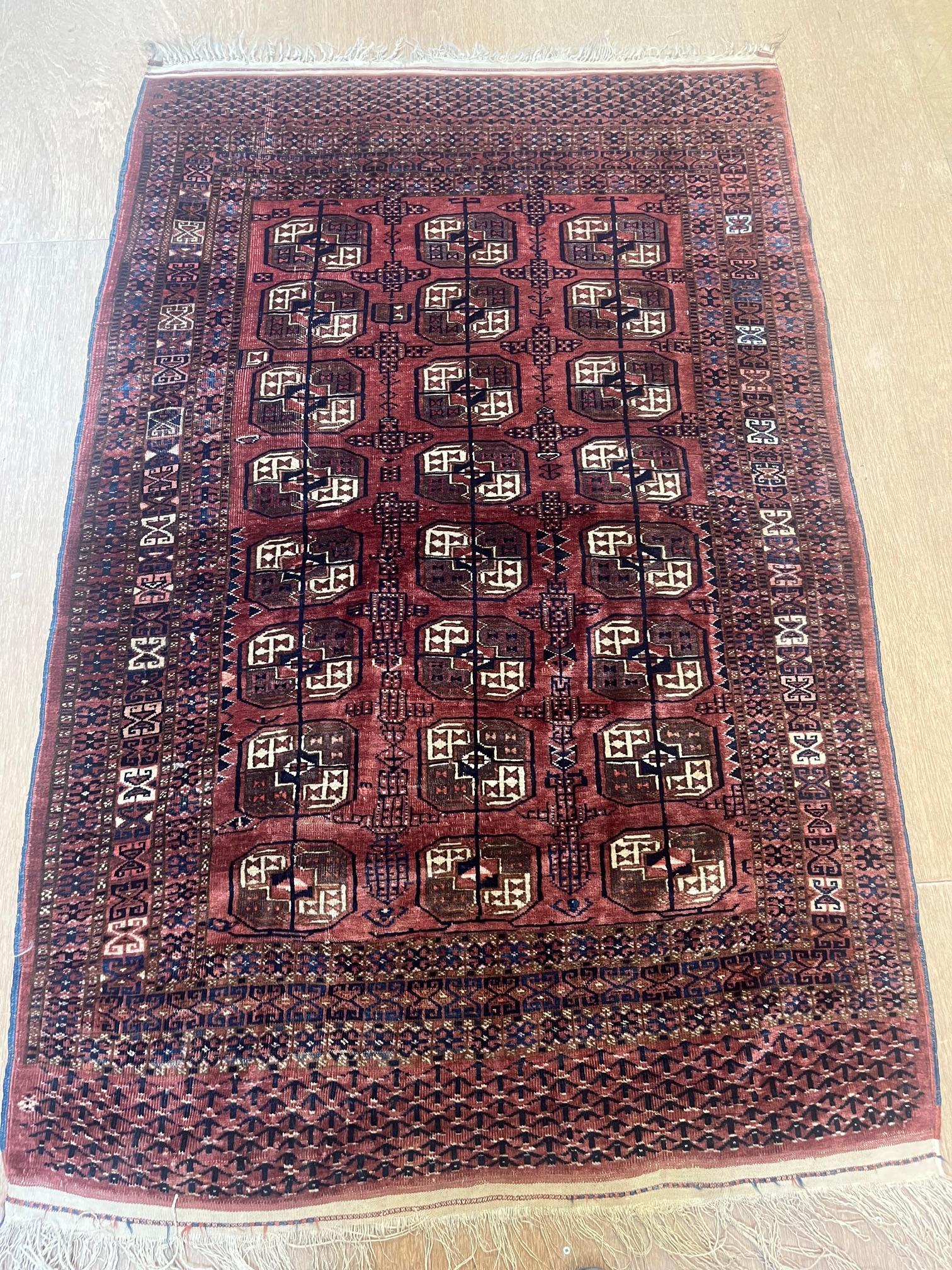 A TEKKE DESIGN RUG, the madder field with a repeating pattern of three rows of quartered Guls within Image