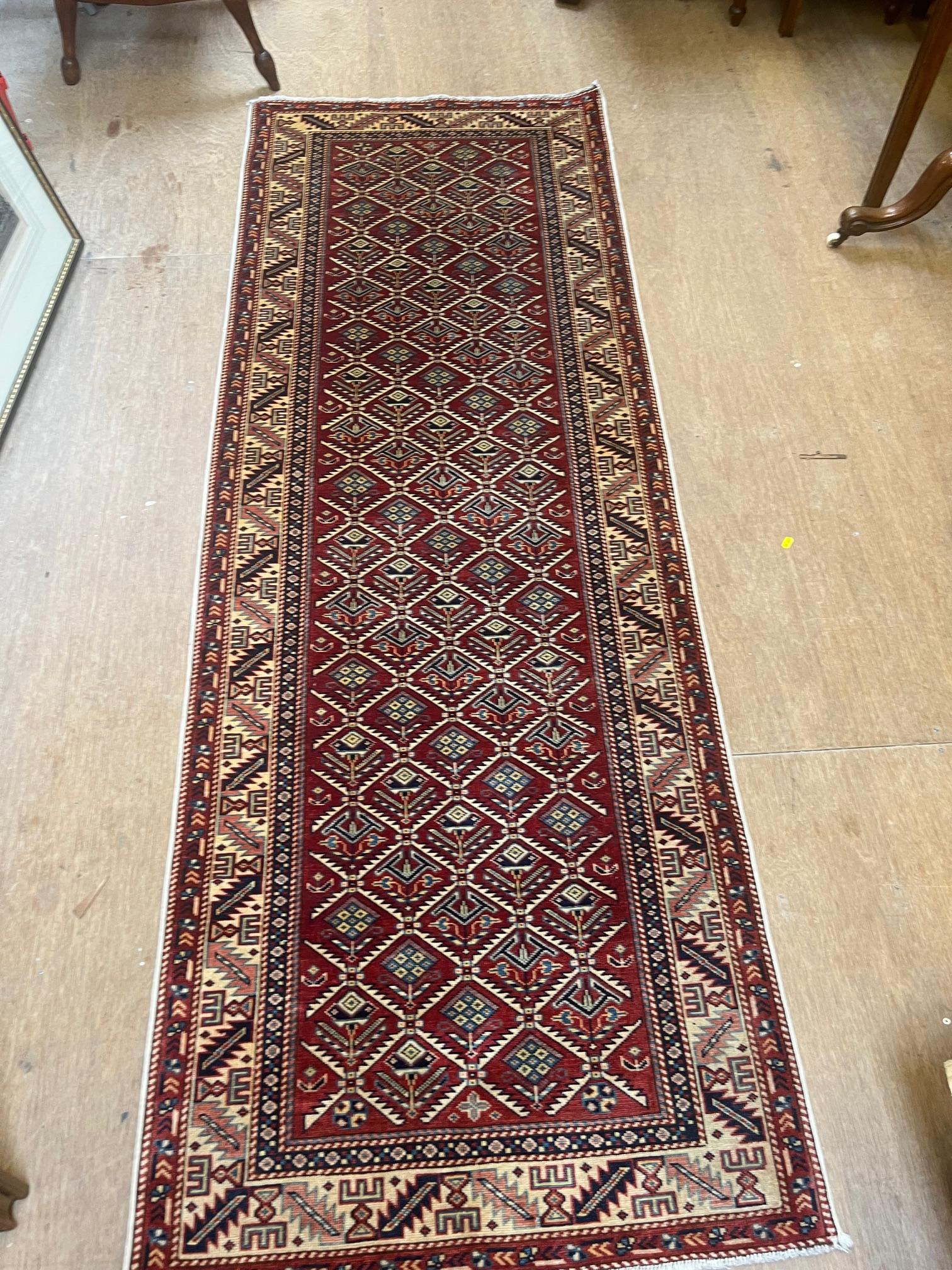A PERSIAN TRIBAL SMALL RUNNER, modern, the claret field with repeating floral lozenge pattern in Image