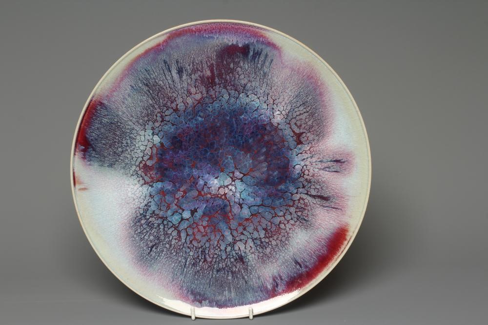 A CHINESE HIGH FIRED SMALL CHARGER of plain circular form with red transitioning to blue glaze Image