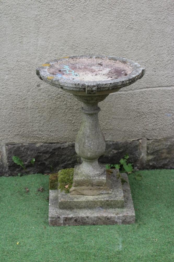 A CAST STONE BIRD BATH, the shallow circular bowl raised on turned baluster stem and stepped square Image