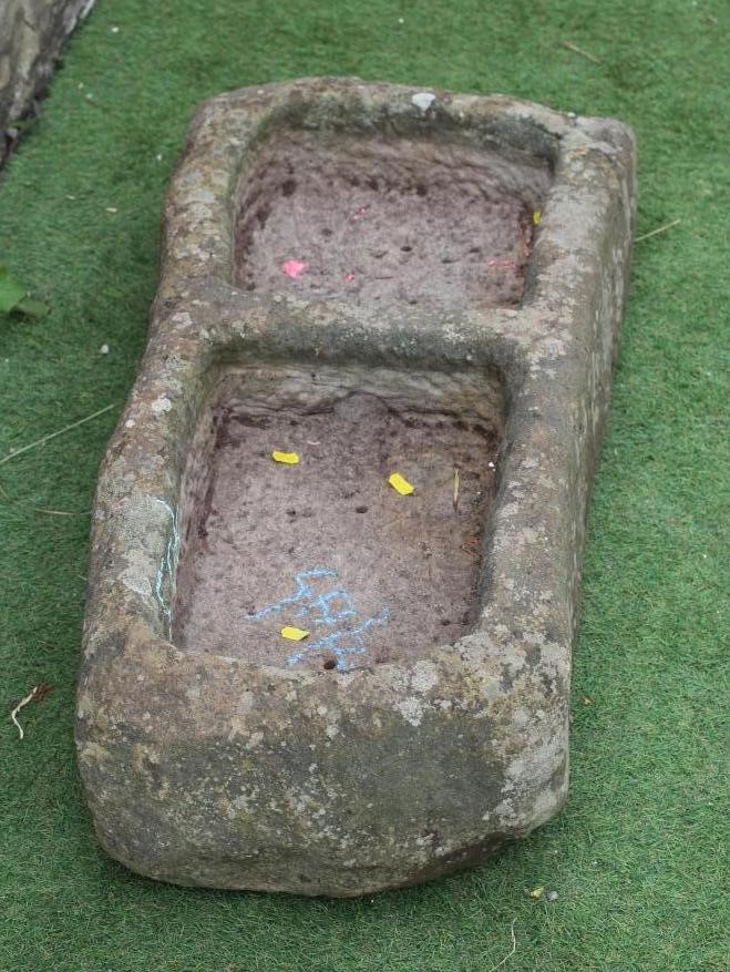 A SANDSTONE TROUGH of rough hewn tapering oblong form with central division, 39" w x 16 1/2" d Image