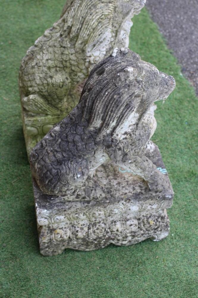 A PAIR OF CAST STONE SEATED BUDDHISTIC LIONS on an oblong base with egg and dart banding, 14 1/2" w Image