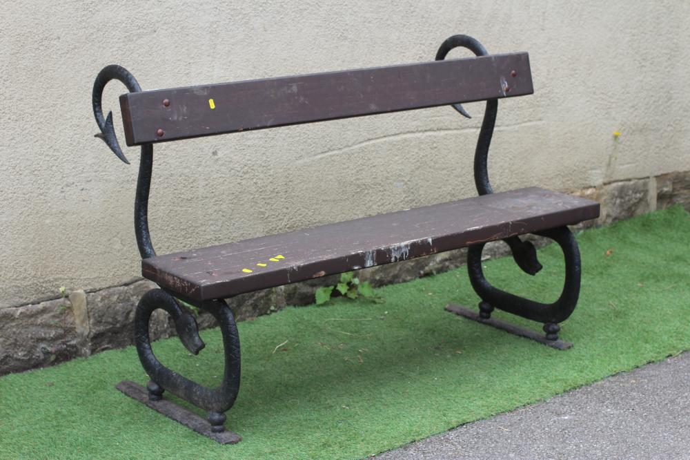A CAST IRON BENCH, the scrolled serpent ends supporting a single wooden plank seat and conforming Image