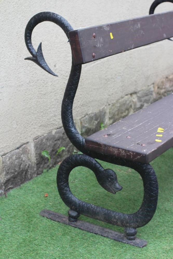 A CAST IRON BENCH, the scrolled serpent ends supporting a single wooden plank seat and conforming Image