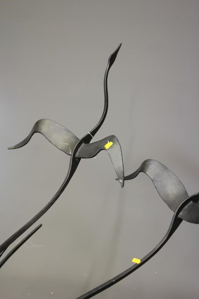 A BLACK PATINATED METAL GARDEN SCULPTURE, modern, modelled as two geese in flight emerging from a Image