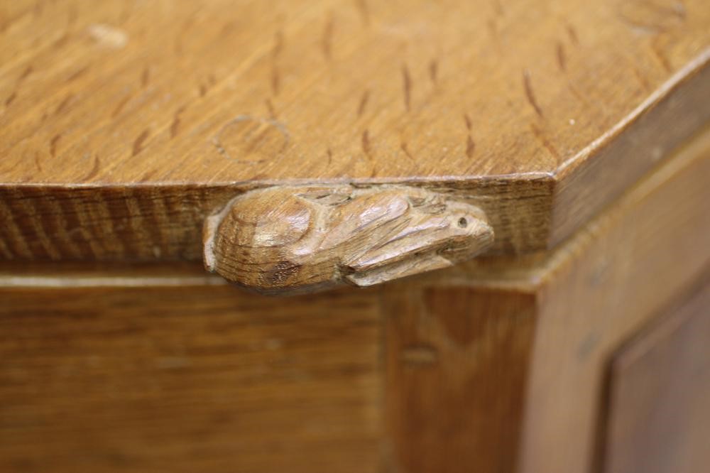 PETER HEAP OF WETWANG - AN ADZED OAK CORNER CUPBOARD of canted multi-panel form with moulded edged Image