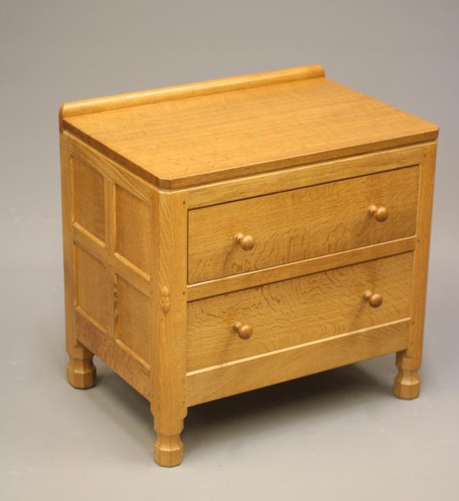 ROBERT THOMPSON - AN ADZED OAK BEDSIDE CHEST of canted oblong form Image